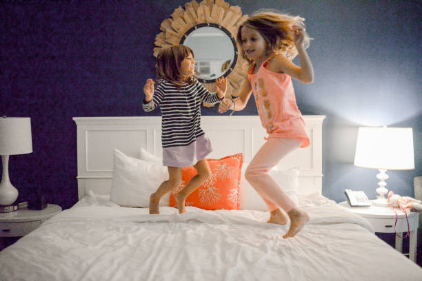 Cute kids elementary age 5 and 7 dance and jump and act silly on the bed of a hotel room in Key West Florida. Happy siblings on vacation fully enjoying the freedom and adventure